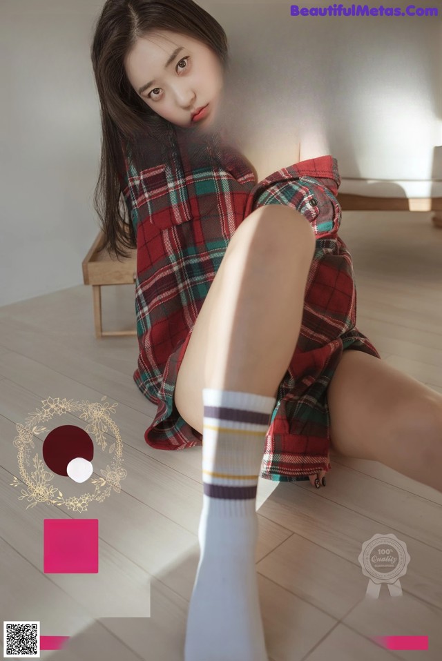 A woman in a plaid shirt and white socks sitting on the floor.