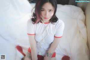 A woman in a red and white outfit laying on a bed.