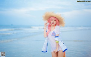 A woman in a straw hat is posing on the beach.