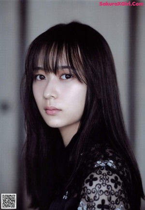 A woman with long black hair sitting on a bench.