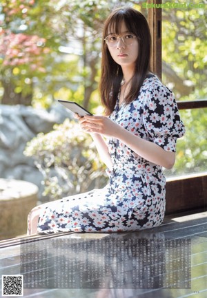 A woman sitting on a bench looking at a tablet.