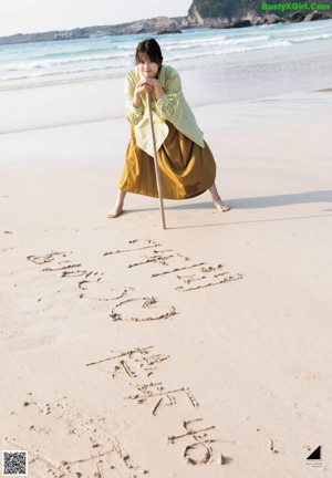 A woman standing on a beach next to the ocean.