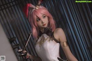 A woman with pink hair sitting on a bed.
