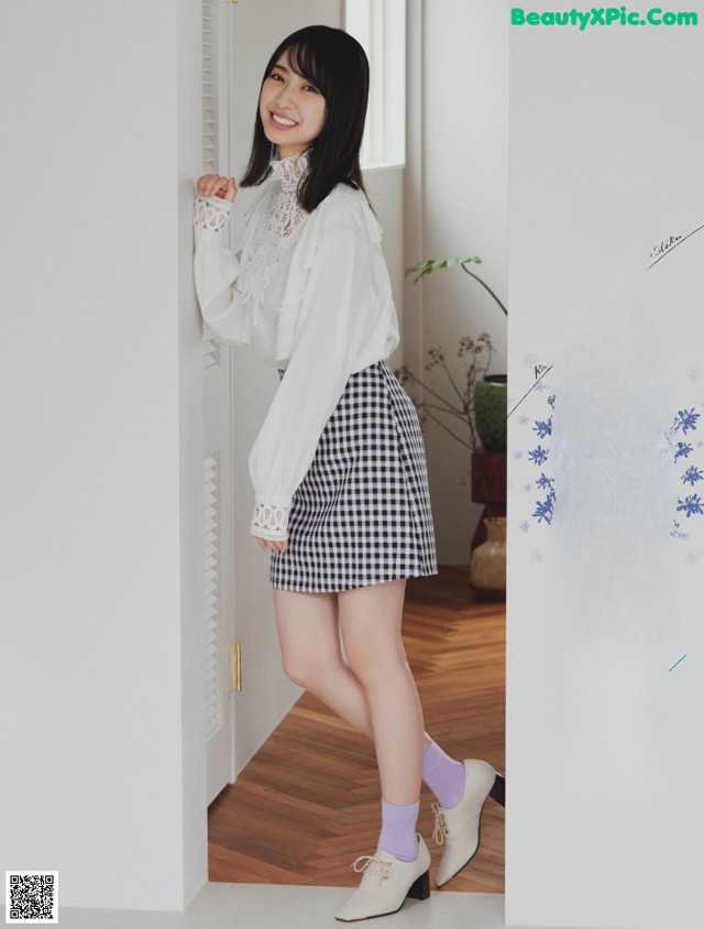 A woman in a white blouse and black and white checkered skirt.