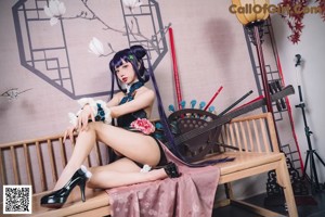 A woman with long purple hair sitting on a chair.