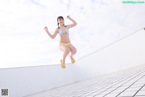 A woman in a bikini standing on a tiled floor.
