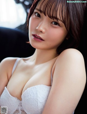 A woman in a pink sweater and black panties laying on a bed.