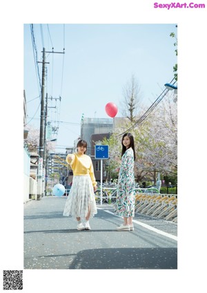 Two women standing next to each other holding balloons.