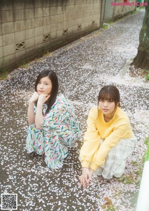 Two young women standing next to each other on a swing.