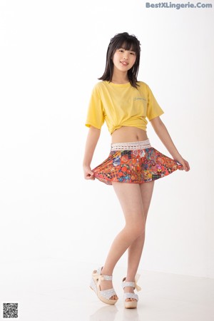 A woman in a yellow shirt and a colorful skirt posing for a picture.