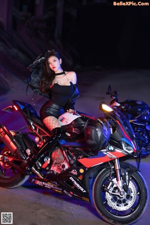A woman in a black bodysuit sitting on a motorcycle.