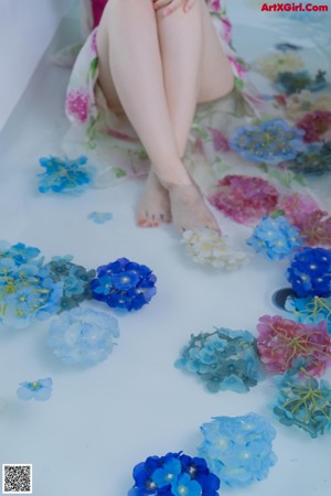 A woman sitting in a bathtub filled with flowers.