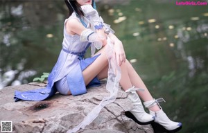 A woman in a blue and white outfit sitting on a ledge.