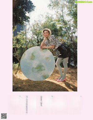 A woman standing next to a large blue ball in a field.