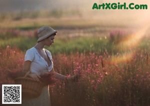 A woman in a straw hat sitting on a bench in a greenhouse.