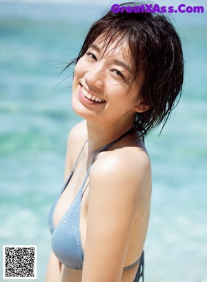 A woman in a tan bikini sitting on the ground.