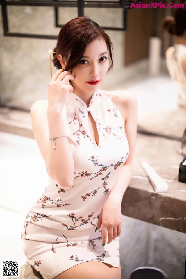 A woman in a white dress sitting on a counter.