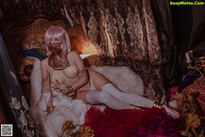 A woman in a white and red outfit sitting on a bed.