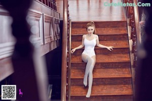 A woman in a white bodysuit is standing on the stairs.