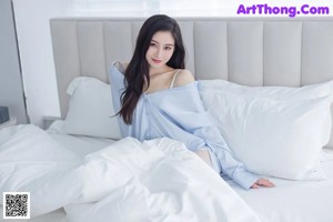 A woman sitting on top of a white bed.