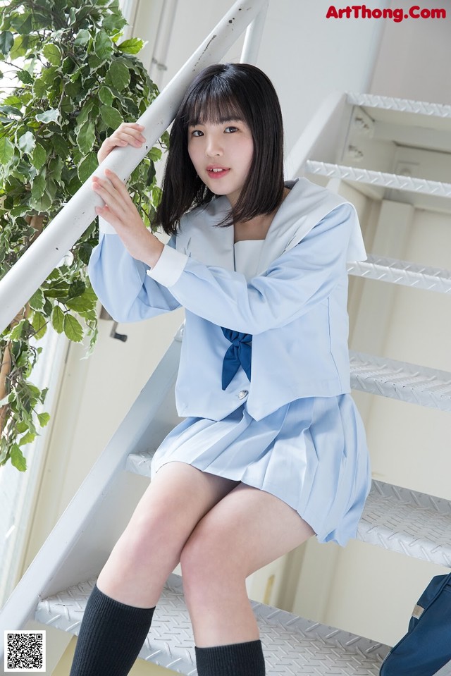 A woman in a school uniform is sitting on the stairs.