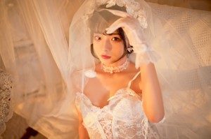 A woman in a white lingerie sitting on a bed.