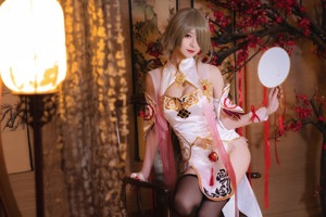 A woman sitting on a bed holding a fan.