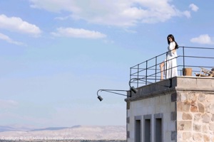 A woman standing next to a wooden barrel on a balcony.