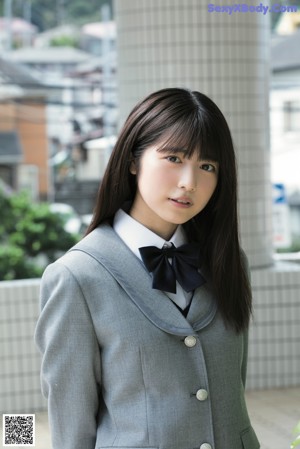 A young woman in a school uniform is posing for a picture.