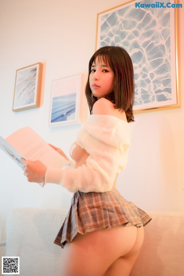 A woman in a school uniform is reading a book.