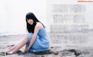 A woman in a blue dress standing on a wooden dock.