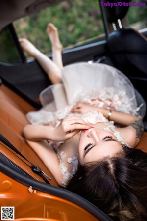 A woman in a white dress sitting in a car.