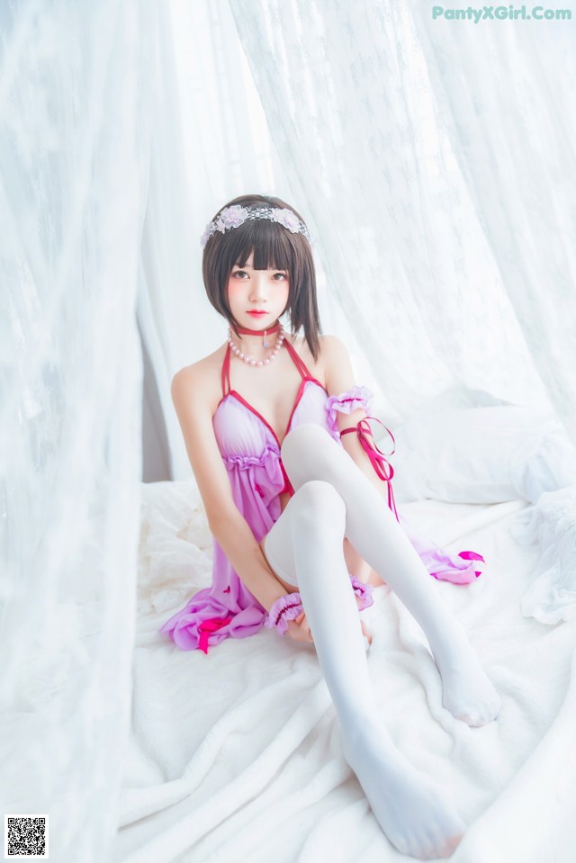 A woman in a pink lingerie sitting on a bed.