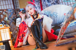 A woman in a kimono sitting on the floor with a fan.