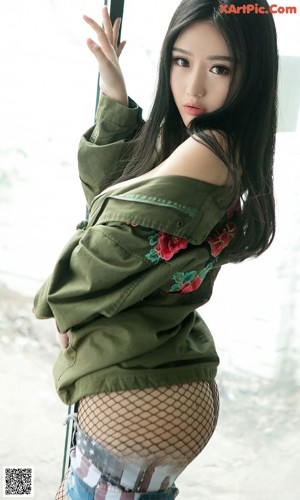 A woman in a green jacket and fishnet stockings posing for a picture.