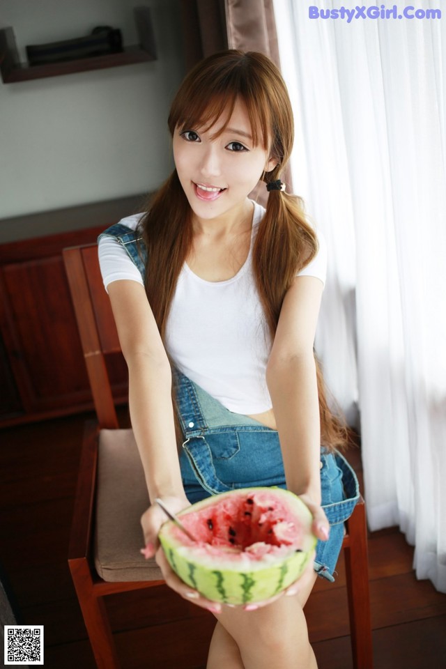 A woman sitting on a chair holding a slice of watermelon.