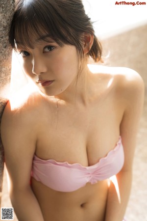 A woman in a pink bikini laying in a bathtub.