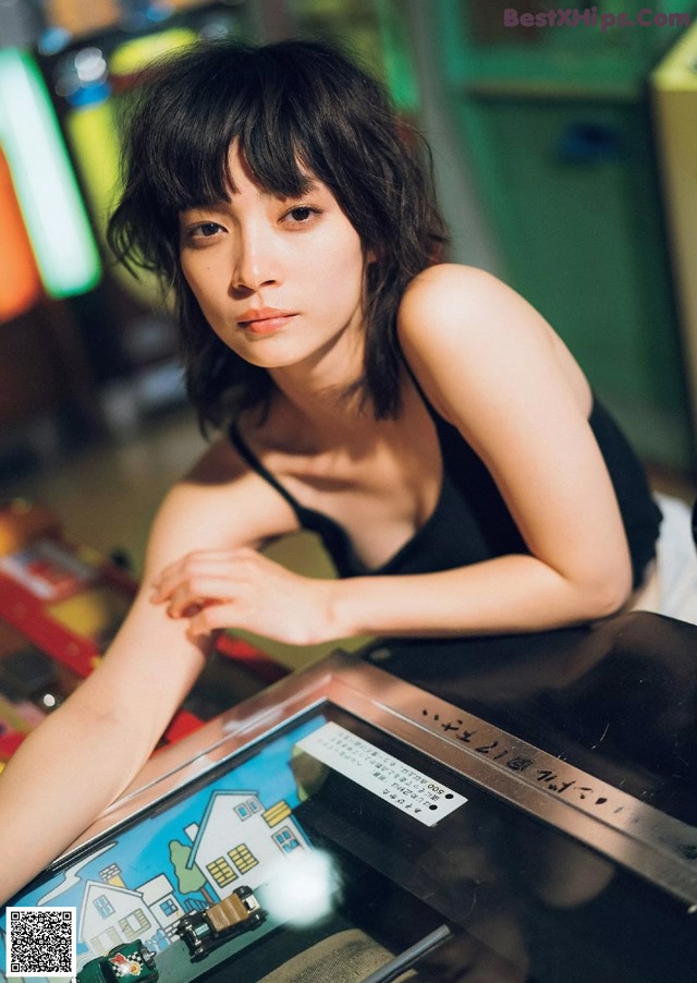 A woman sitting at a table with a pinball machine.