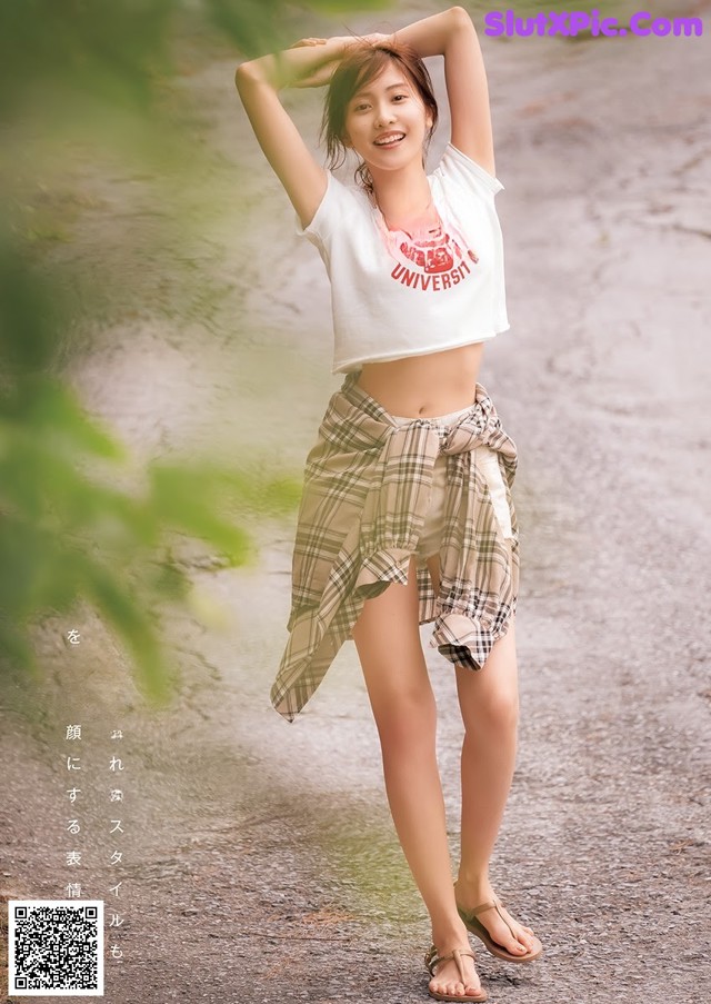 A woman in a white shirt and plaid skirt posing for a picture.