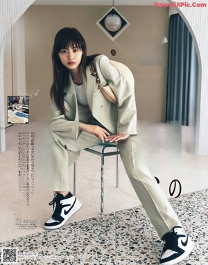 A woman in a white dress and black boots posing for a magazine.